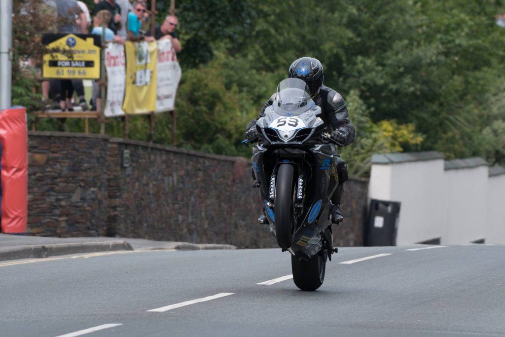 Motorcyclist doing a wheelie at the Isle of Man TT, one of the bucket List events for Two-Wheel Addicts