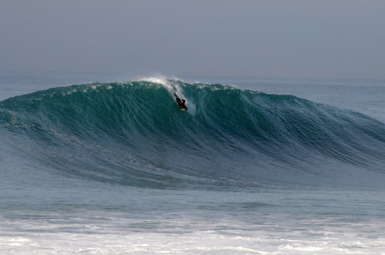 A bodyboarder catches a wave at Nazaré best surf beaches in Portugal